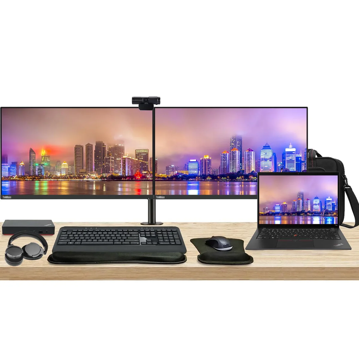 Open laptop beside two monitors on a shared stand with dock keyboard mouse webcam headphones bag and wrist rests