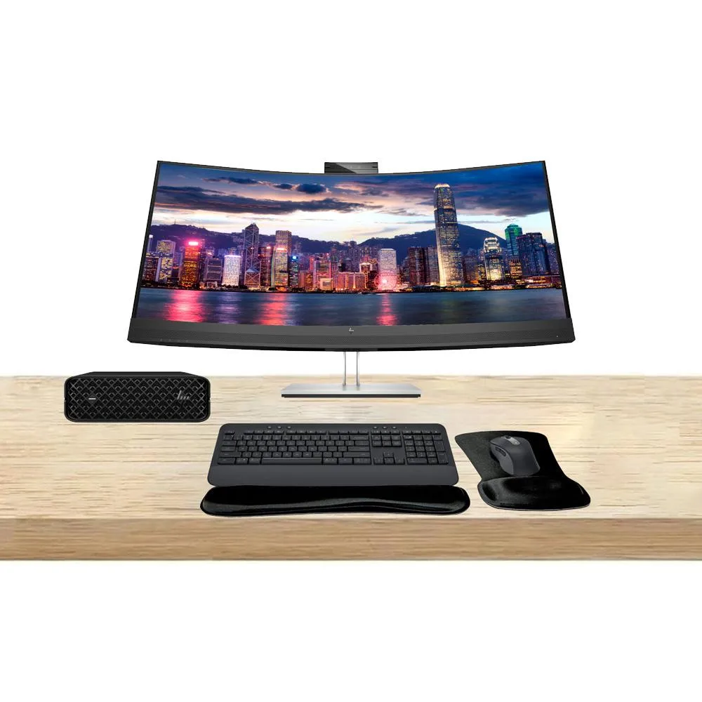 Compact silver mini PC beside a 34-inch curved ultrawide monitor with slim bezels