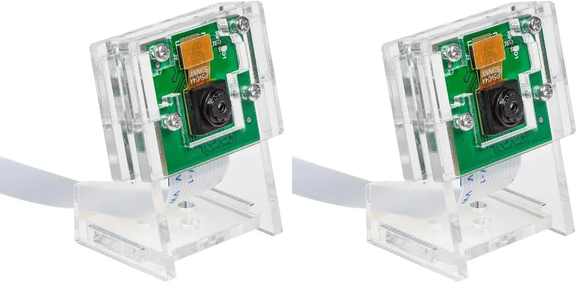 Two small green circuit boards with camera lenses in clear acrylic cases, flat ribbon cables attached