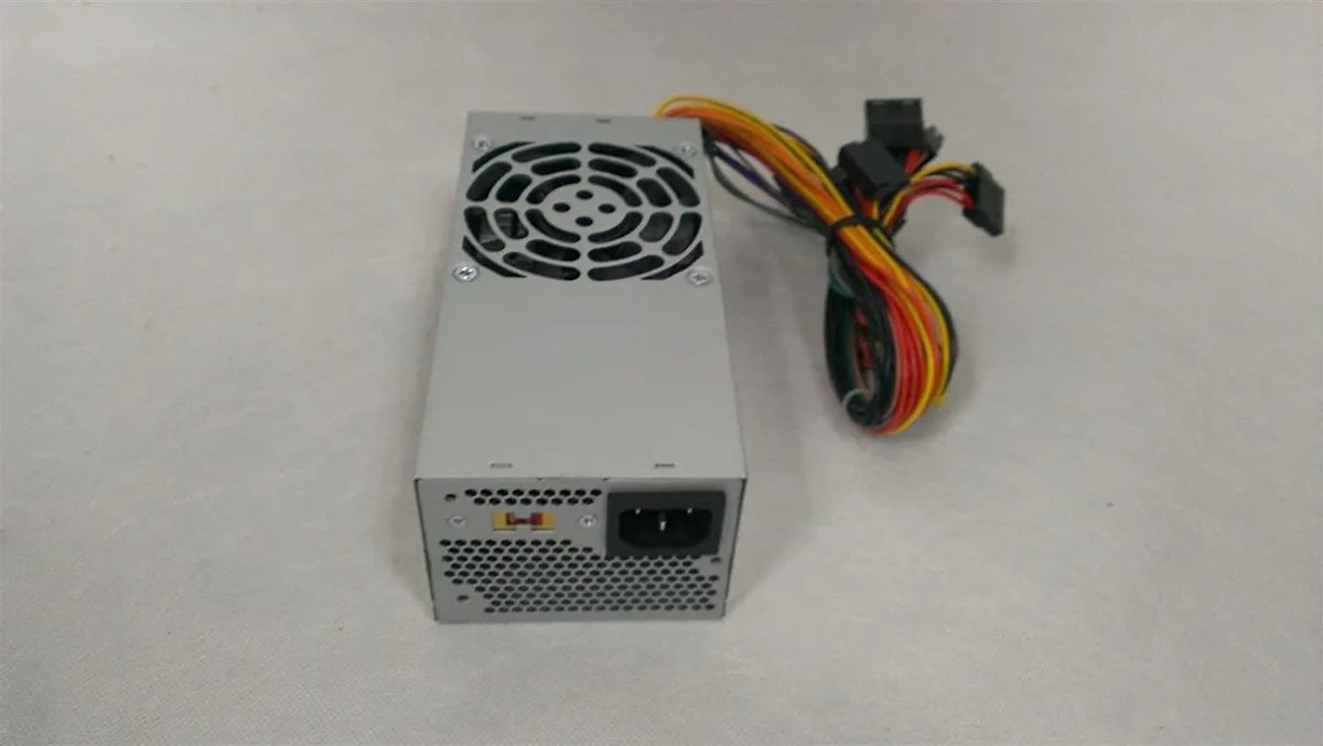 Compact TFX power supply unit in matte black metal casing with 80mm cooling fan and multiple cable connectors visible