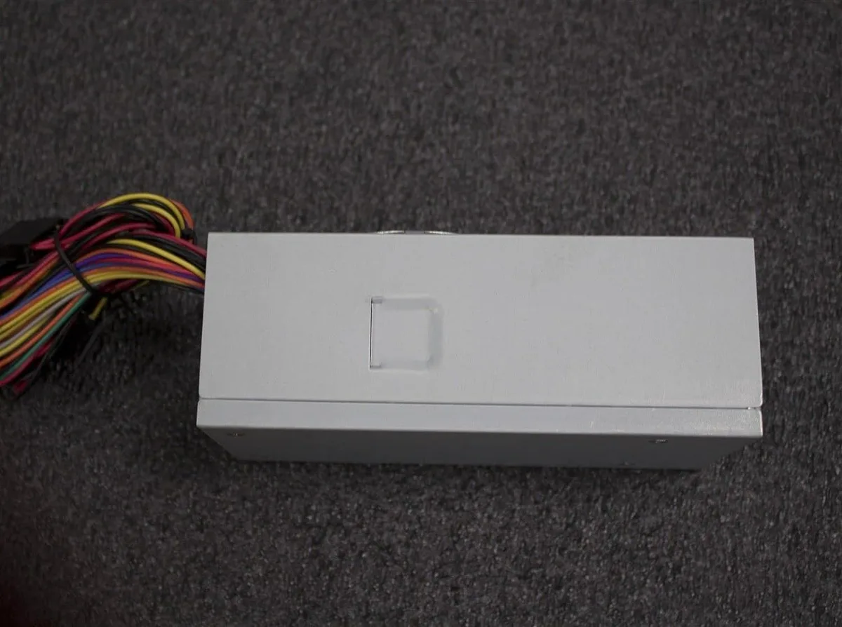 Compact TFX power supply unit in metal casing with 80mm fan grille and cable bundle visible