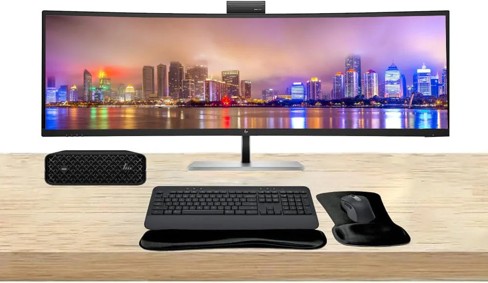 Compact silver mini PC, large 49-inch curved ultrawide monitor, wireless keyboard and mouse set