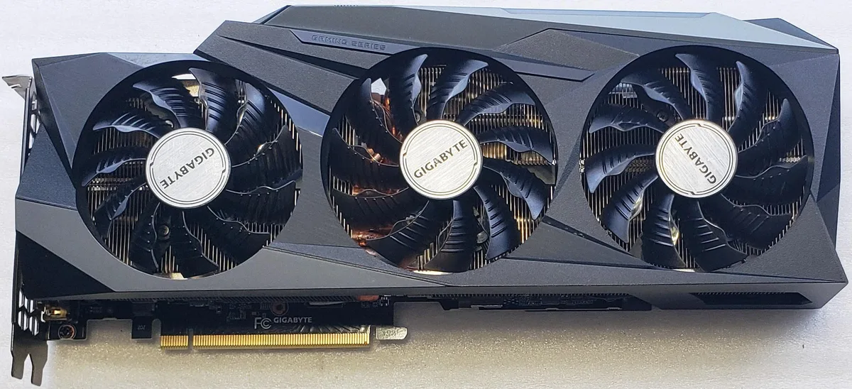 Triple-fan graphics card, dark shroud, metal backplate, visible wear marks
