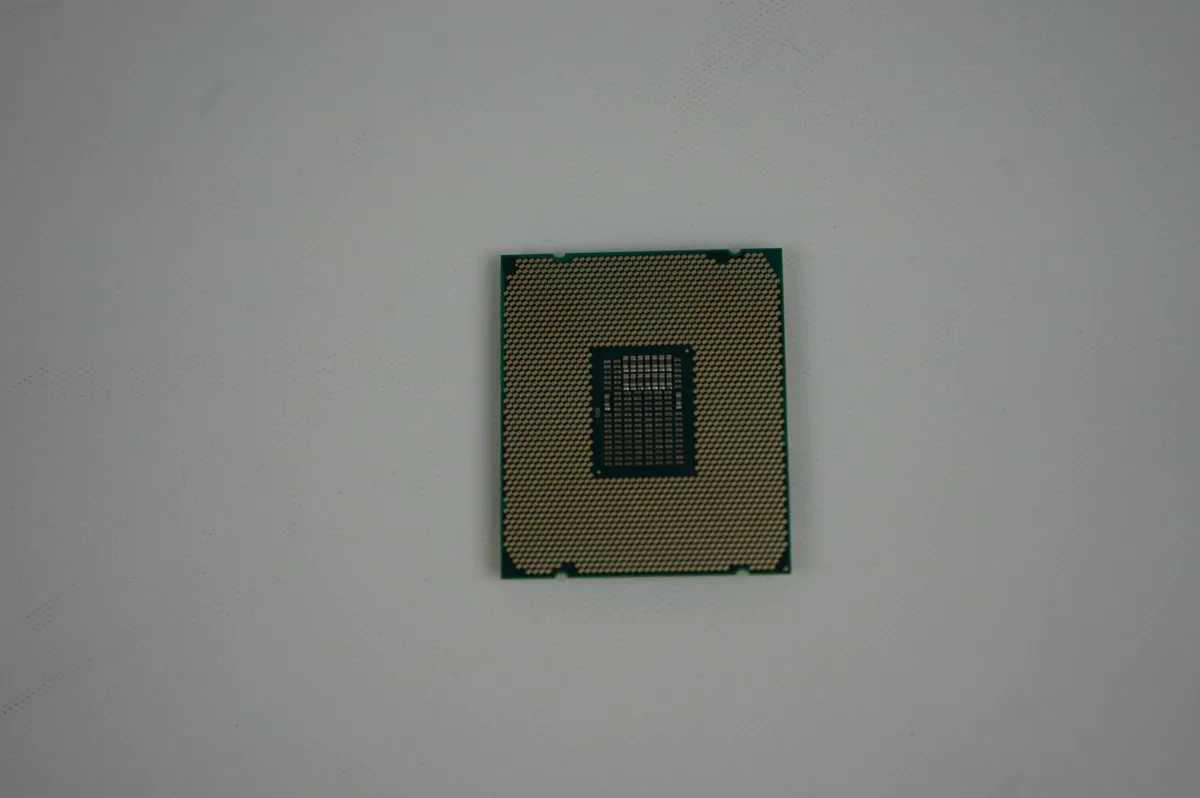Square metallic processor with gold contact pads and silver heat spreader, text printed on top