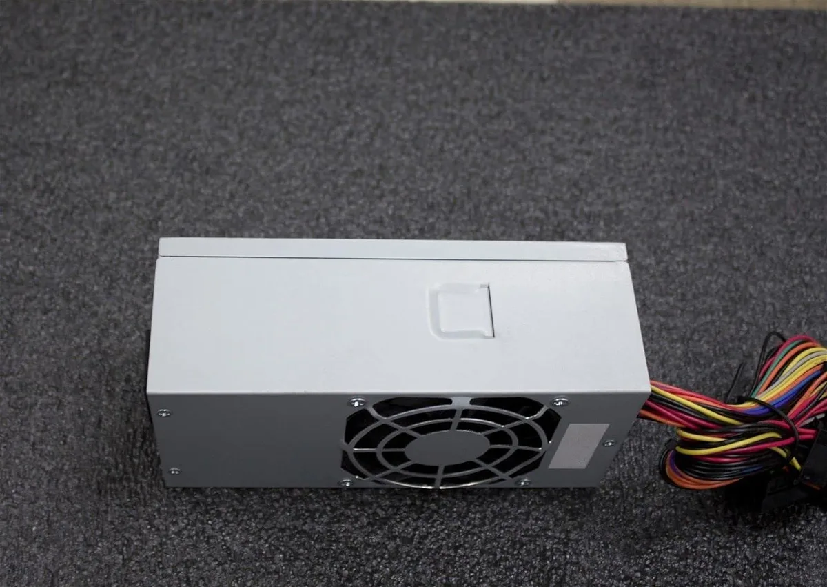 Compact silver TFX power supply with 20+4 pin and SATA cables visible