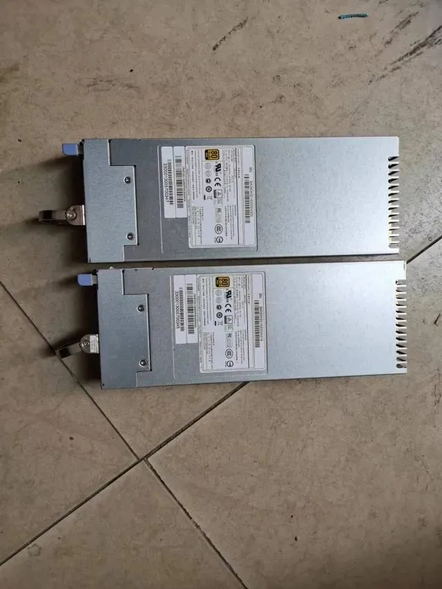 Silver rectangular server power supply unit with ventilation grille and label showing model YM-2102F 1000W