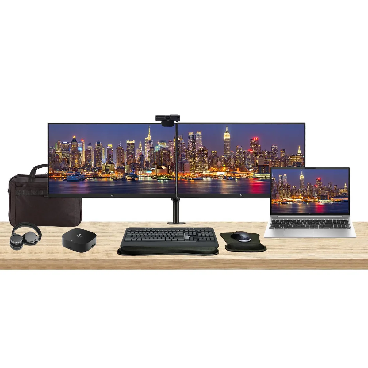 Open laptop beside two monitors on a dual stand with dock keyboard mouse webcam headphones and bag