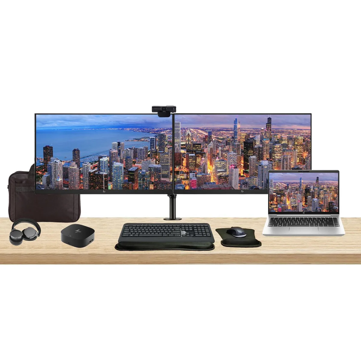 Silver 14-inch laptop open beside two 27-inch monitors on a dual-arm stand, wireless keyboard and mouse with gel rest, webcam
