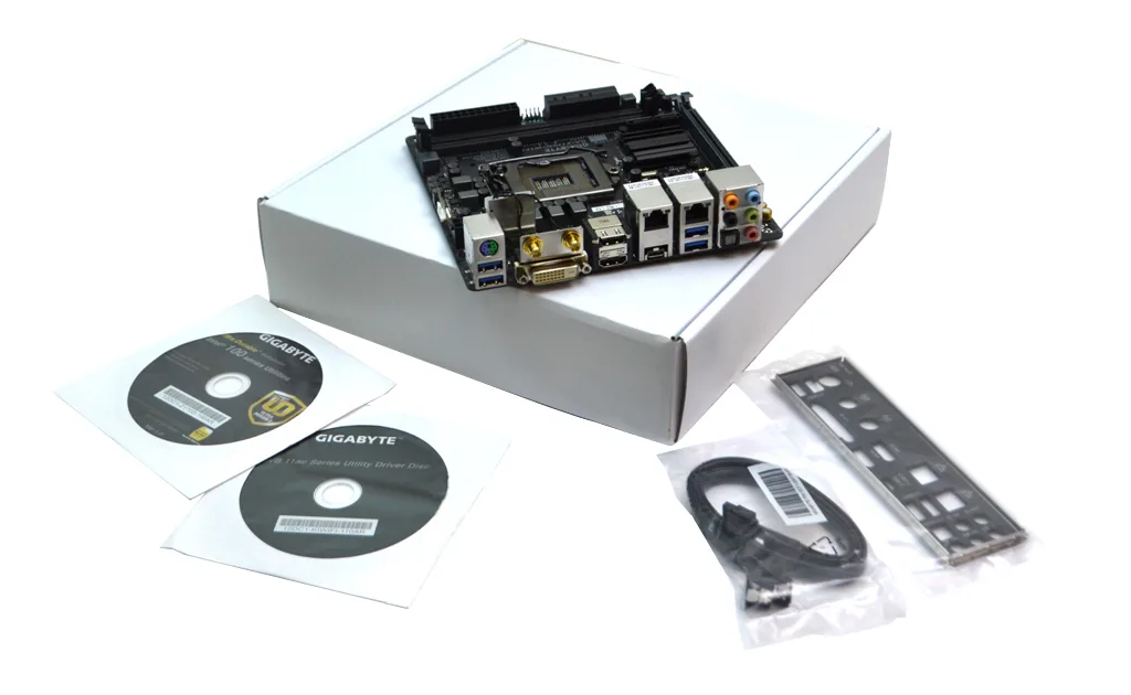 Mini-ITX motherboard in white box packaging, green PCB with black heatsinks and silver I/O shield