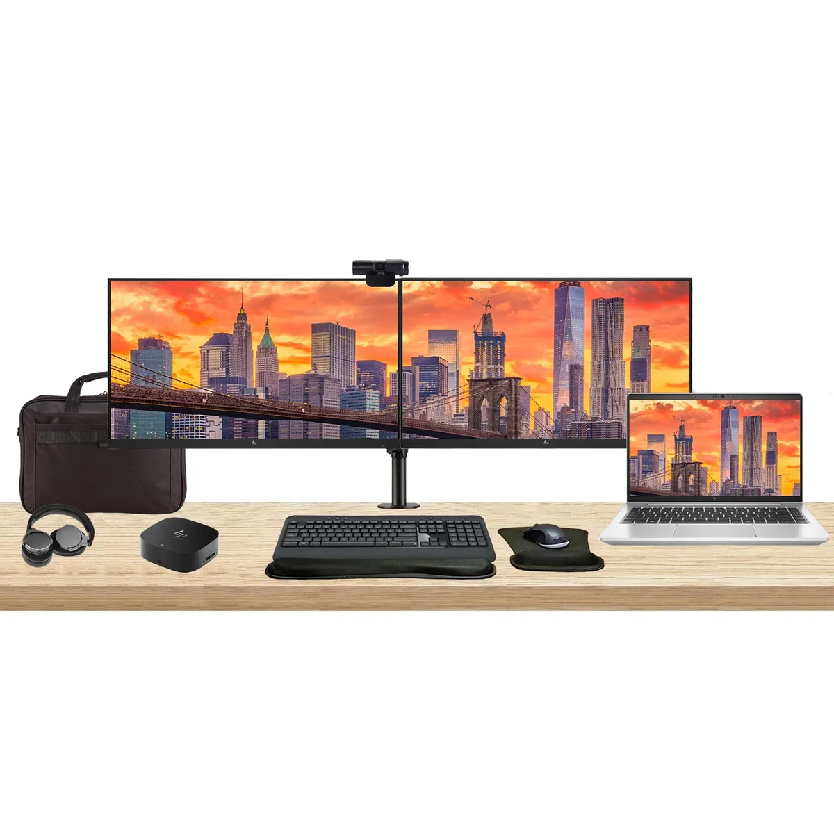 Silver 14-inch laptop open beside two 24-inch monitors on a dual desk mount, with a compact dock, wireless keyboard and mouse, webcam