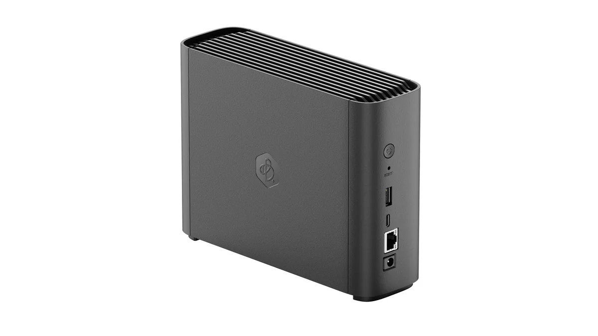 Compact white desktop NAS unit with rounded edges, front status light, rear Ethernet and USB ports