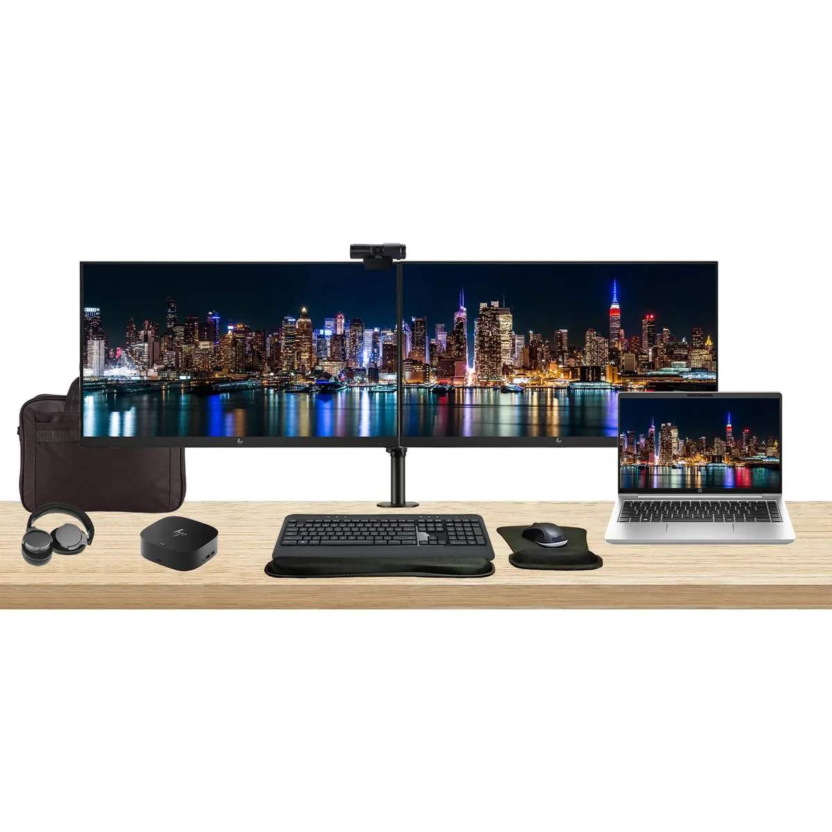 Open laptop beside two monitors on a dual clamp stand with dock keyboard mouse webcam headphones gel pad and briefcase