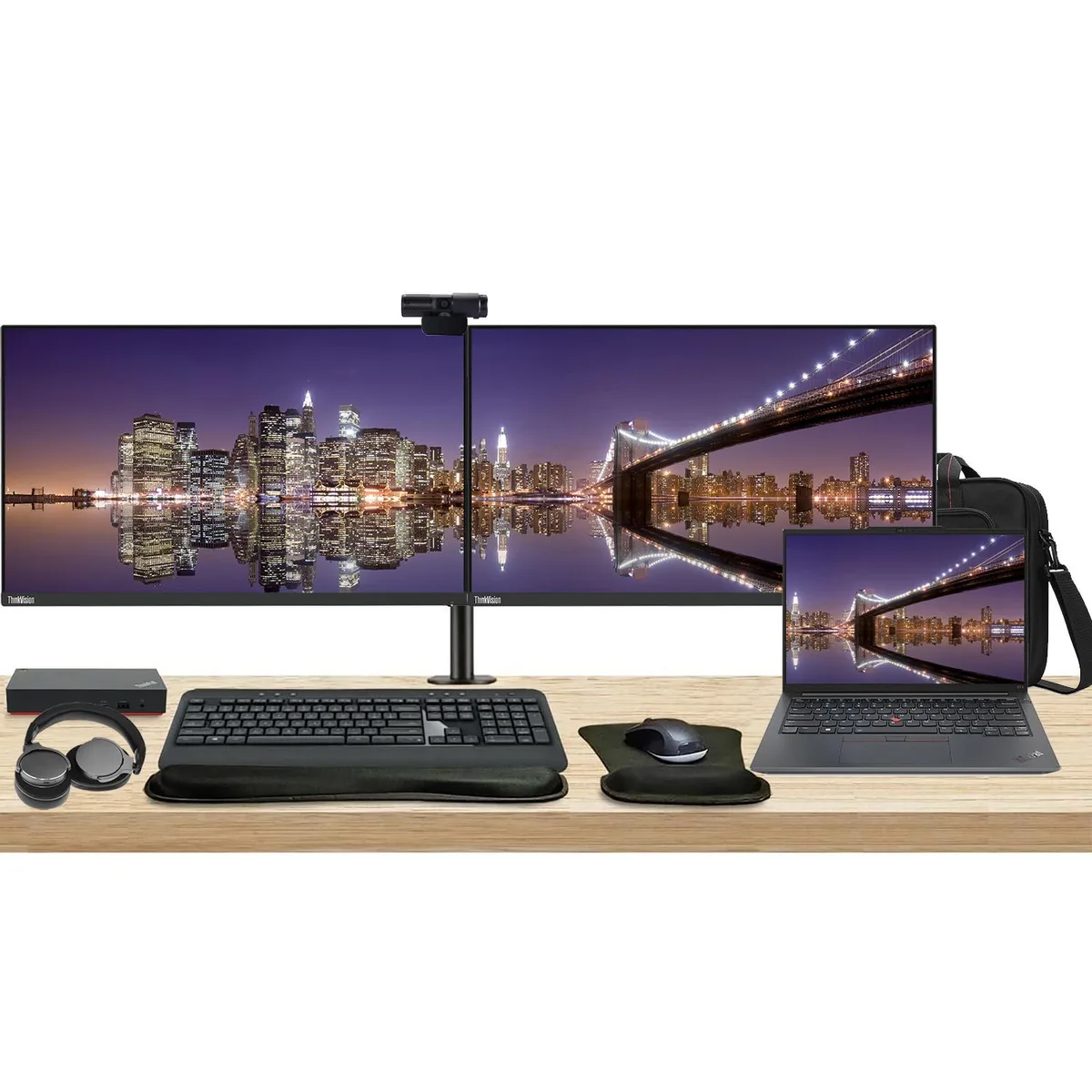 Open laptop beside two monitors on a shared stand with dock keyboard mouse webcam headphones wrist rest and bag