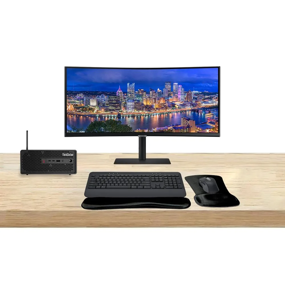 Compact silver workstation tower beside 34-inch curved ultrawide monitor with wireless keyboard and mouse