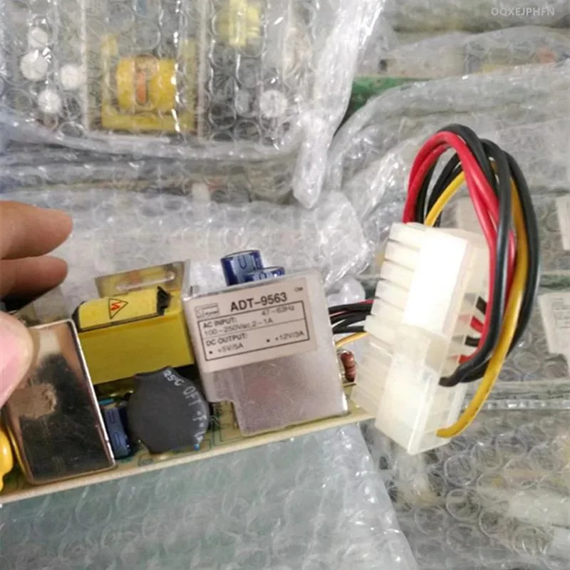 Black rectangular ATX power supply unit with cooling vents and label showing model ADT-9563