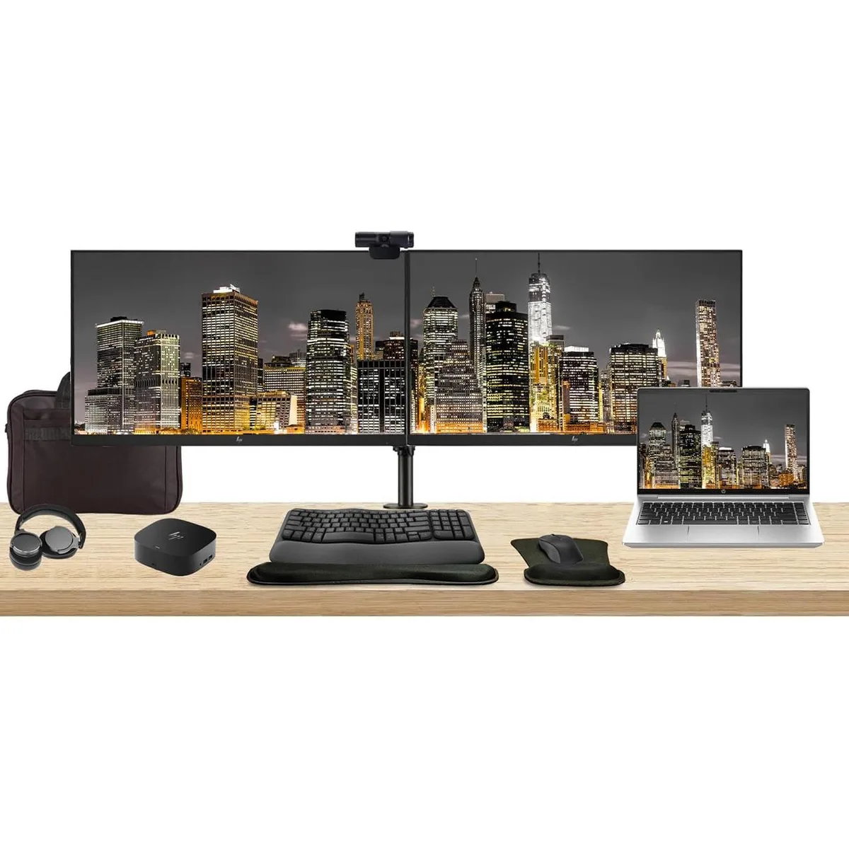 Silver 14-inch laptop open beside two 27-inch monitors on a dual arm stand with dock, wireless keyboard, mouse, webcam