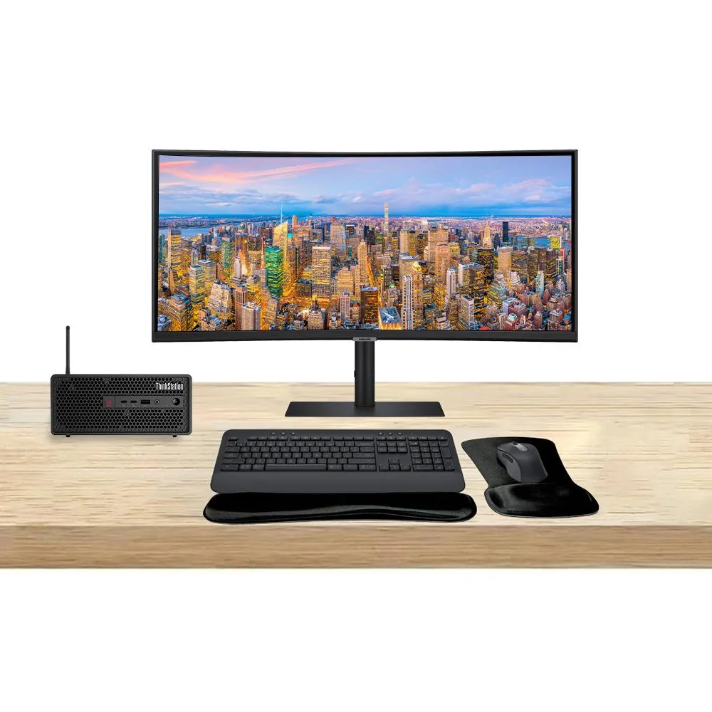 Compact silver mini-tower beside 49-inch curved ultrawide monitor with wireless keyboard and mouse