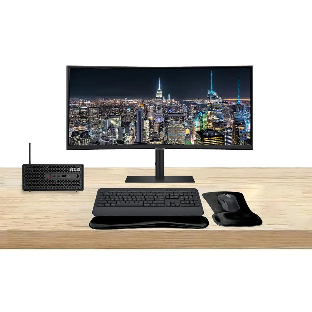 Compact silver desktop tower beside a wide 49-inch curved ultrawide monitor with wireless keyboard and mouse