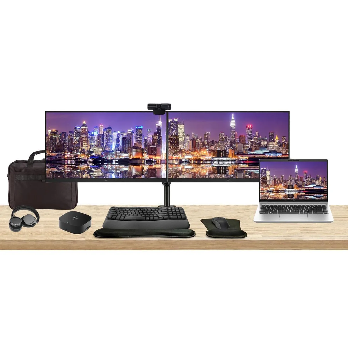 Silver 14 inch laptop open beside two 24 inch monitors on a dual stand with dock keyboard mouse webcam headphones gel pad and briefcase