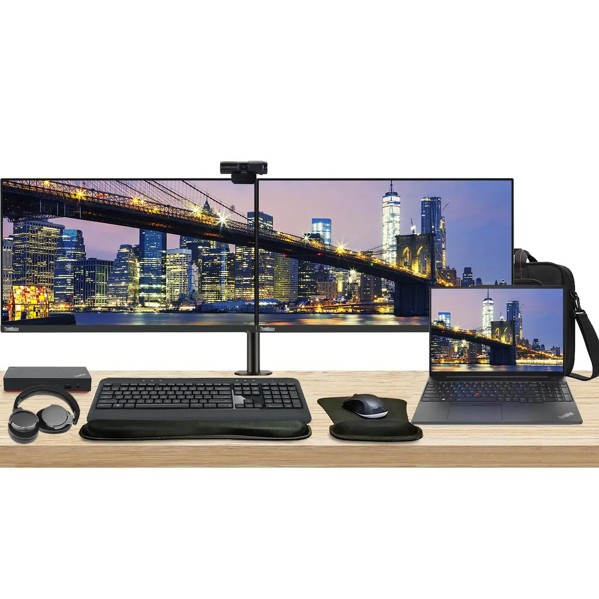 Open laptop beside two monitors on a dual arm stand with dock keyboard mouse webcam headphones bag and wrist rest