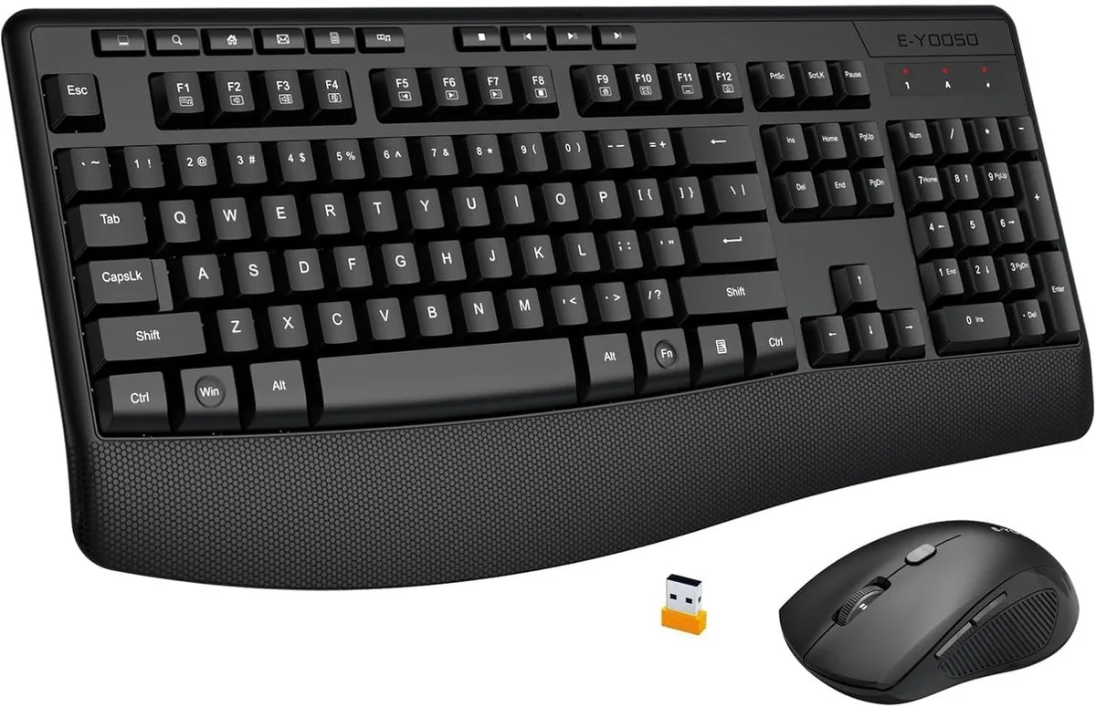 Black full-size wireless keyboard with integrated wrist rest and matching mouse on a desk