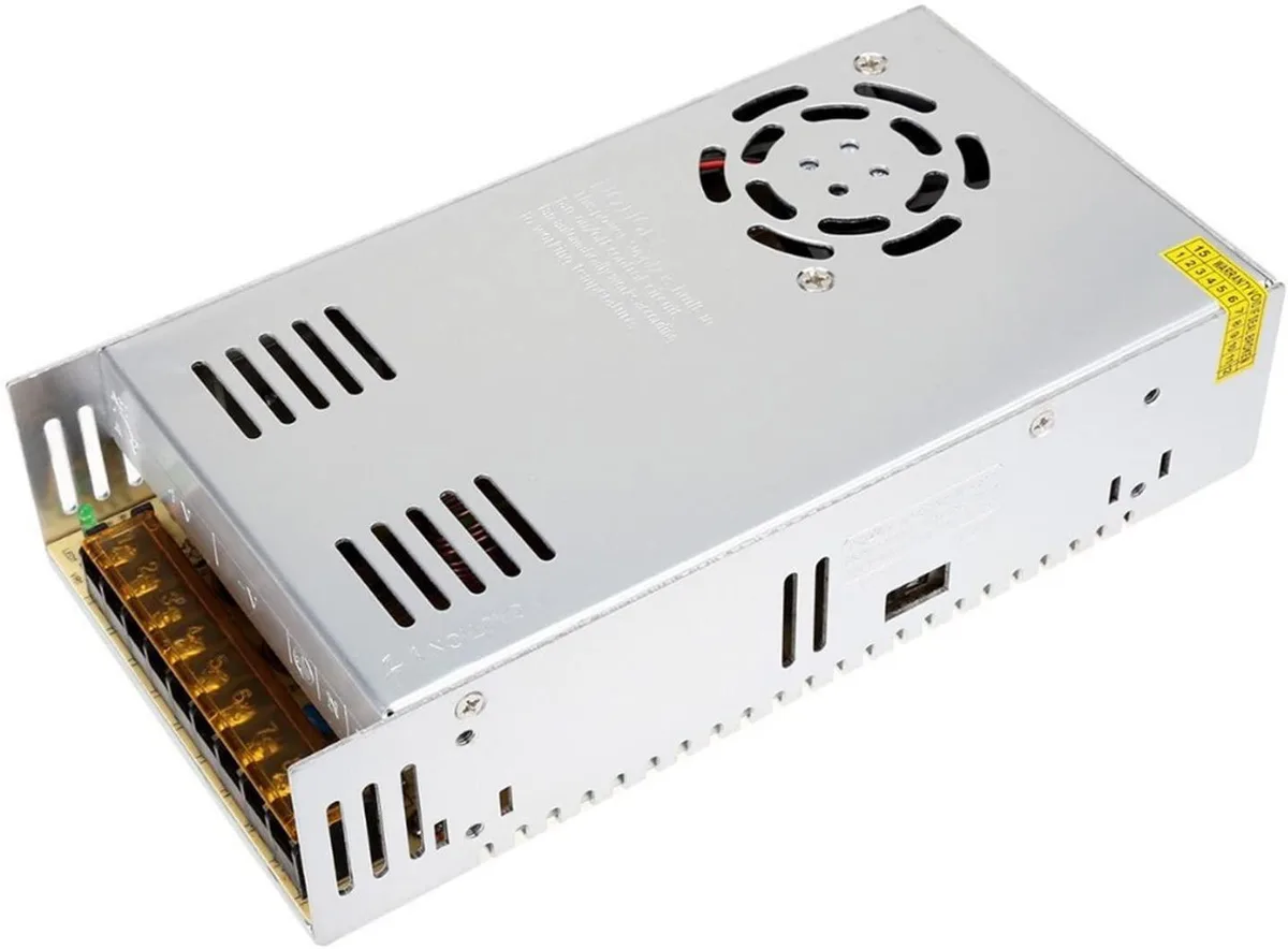 Rectangular silver metal power supply unit with cooling fan and terminal connections